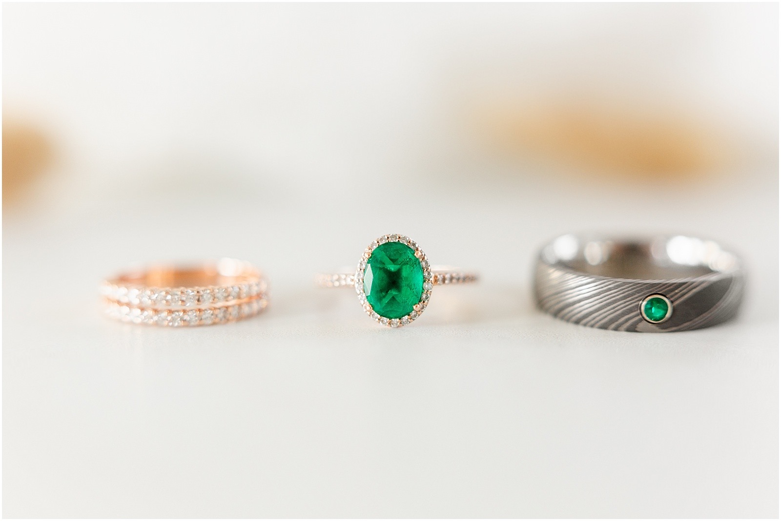 emerald engagement ring with diamond wedding band and groom's wedding ring