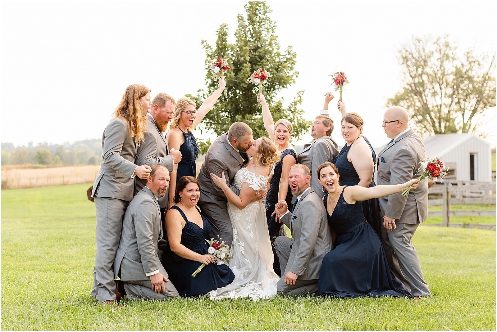 bride and groom kissing while wedding party cheers