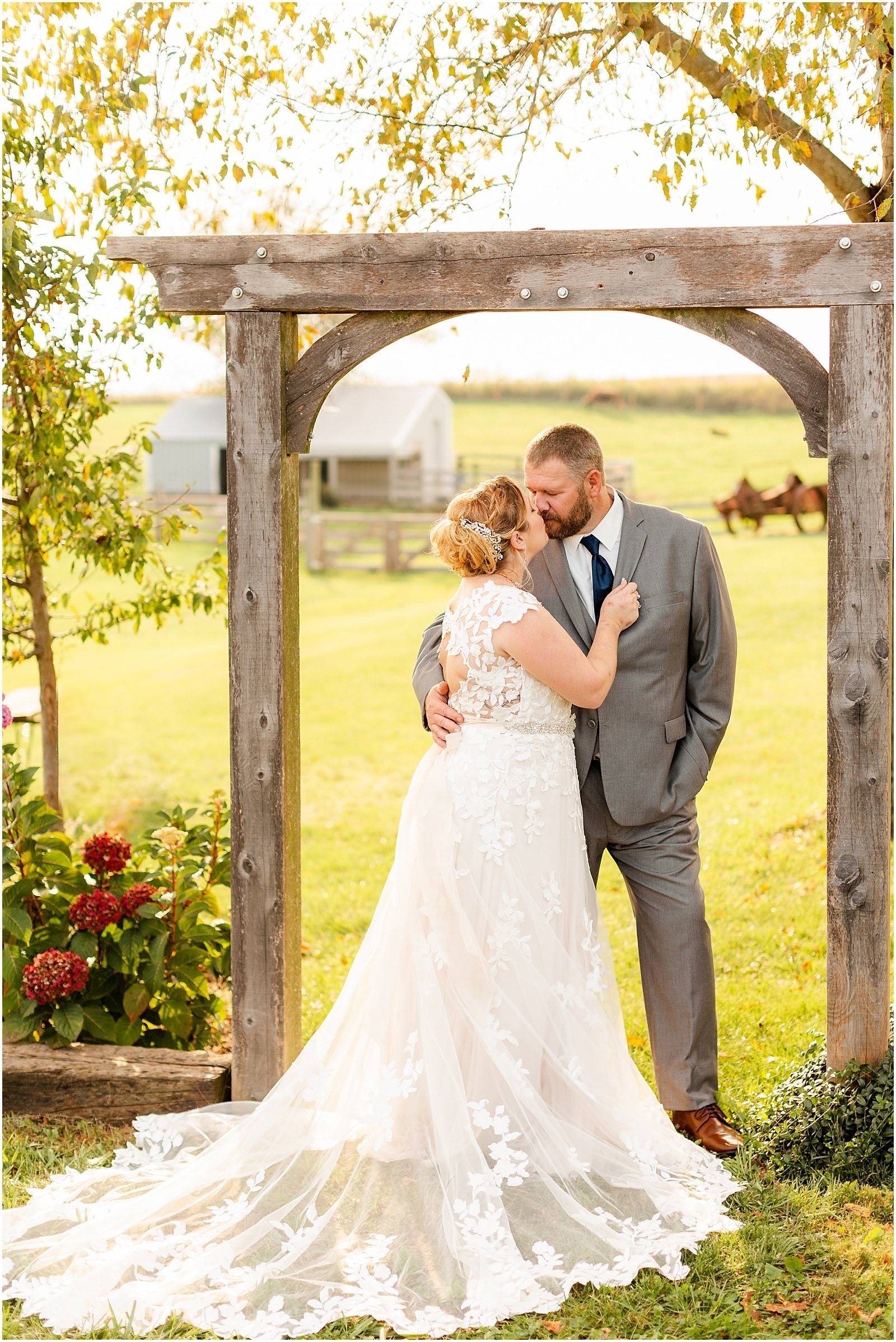 bride and groom kissing under wooden arch outdoors